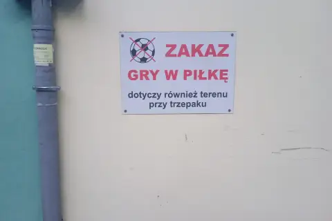Tabliczka z przekreśloną piłką informuje o zakazie gry w piłkę pod oknami i przy trzepaku.