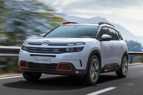 Biały Citroen C5 Aircross z czerwonymi akcentami pędzi po drodze. Wiele osób szuka o nim **citroen c5 aircross opinie**.