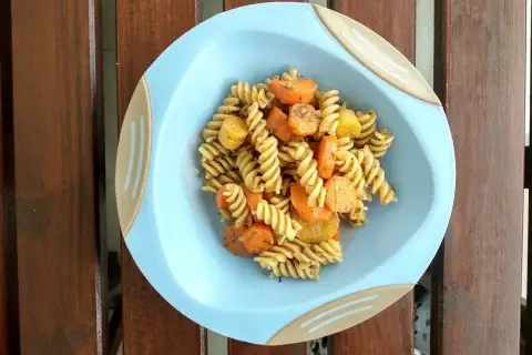 Makaron fusilli z marchewką i ziemniakami na niebieskim talerzyku.