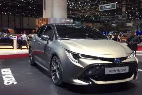 Elegancki, srebrny Auris Hybrid prezentowany na targach motoryzacyjnych. Na podłodze widoczny napis "NEW AURIS WORLD PREMIERE".