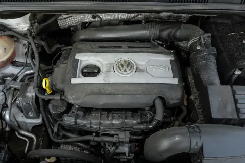 Silnik 2.0 TSI Volkswagena, widok z góry. Widać pokrywę silnika z logo VW i napisem TSI, przewody i inne elementy komory silnika.