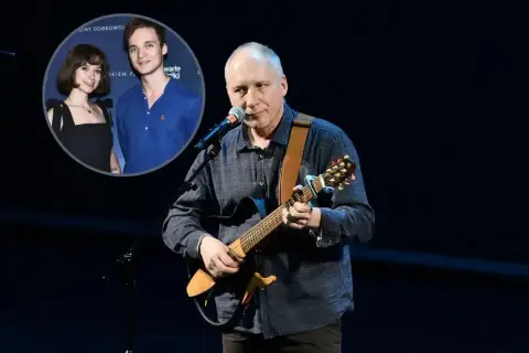 Kuba Sienkiewicz gra na gitarze, a w tle widać jego dzieci.