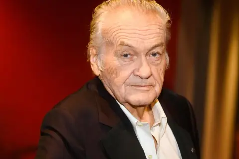 Jerzy Skolimowski, reżyser znany z wyrazistych filmów, na tle czerwonej kurtyny.