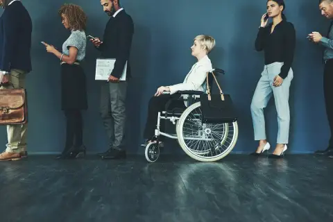 Różne rodzaje niepełnosprawności w kolejce do pracy: osoba na wózku inwalidzkim i inni kandydaci.