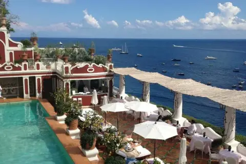 Terraza del Hotel Europa con piscina, tumbonas y vistas al mar azul con barcos.