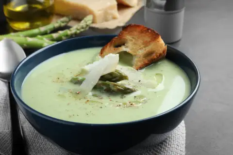 Aksamitny zupa krem ze szparagów zielonych, udekorowana świeżymi szparagami, parmezanem i grzanką. Idealna na wiosenny obiad.