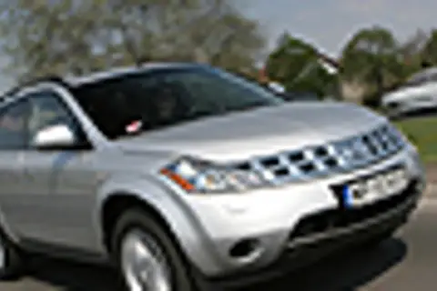 Srebrny Nissan Murano 3.5 V6 na drodze, z drzewami i innymi samochodami w tle.