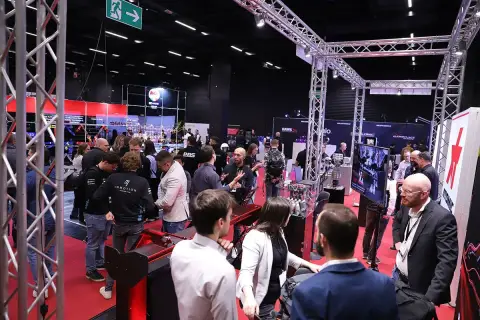 Besucher auf der Professional Motorsport World Expo, die sich über Rennsporttechnologie informieren.