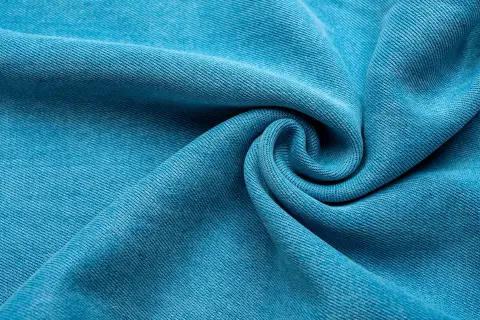 Textura de tela Tencel azul vibrante, suave y con caída, que evoca la comodidad y sostenibilidad de este tejido.