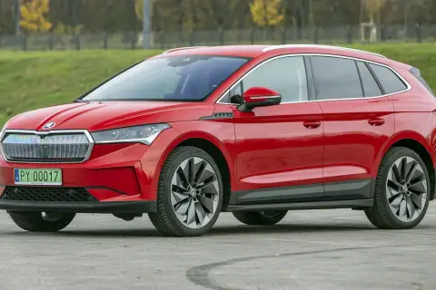 Czerwona Skoda Enyaq na tle zieleni. Sprawdź aktualną skoda enyaq cena i wybierz swój wymarzony samochód elektryczny.