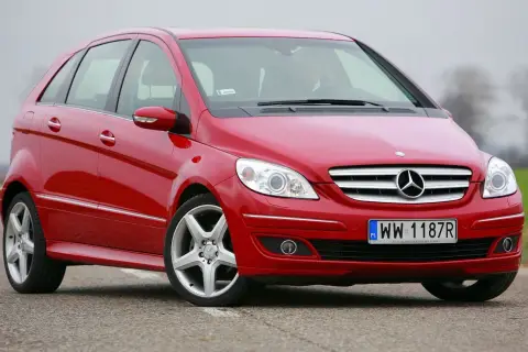 Czerwony Mercedes W245 na drodze, z widocznym grillem i reflektorami.