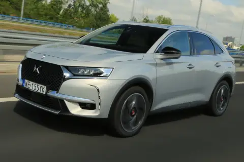 Srebrny DS 7 Crossback E-Tense pędzi autostradą, jego elegancka linia podkreślona przez dynamiczne światła.