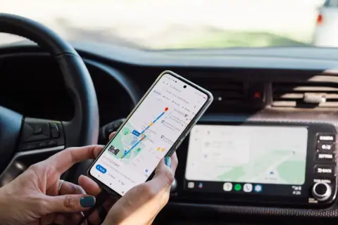 Ręce trzymają telefon z nawigacją, aby uniknąć mandatu za telefon podczas jazdy.