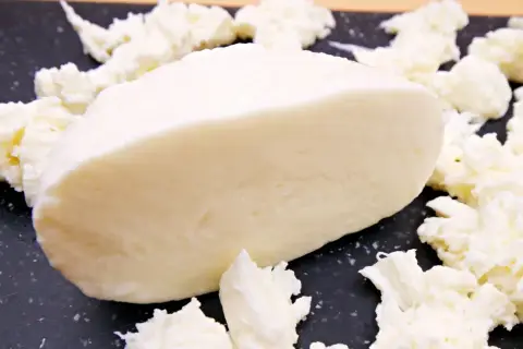 Kawałek świeżej mozzarelli otoczony postrzępionymi kawałkami sera. Idealny do sałatek, a jego mozzarella kcal sprawia, że jest to zdrowy wybór.