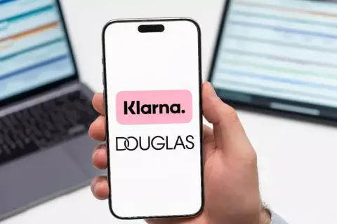 Dłoń trzyma smartfon z logo Klarna i Douglas. To ułatwia zakupy, jak douglas paypo.
