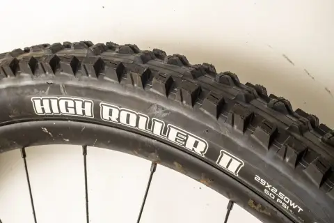 Close-up of a Maxxis High Roller II tire, ready for a review. Its aggressive tread promises excellent grip on challenging trails.