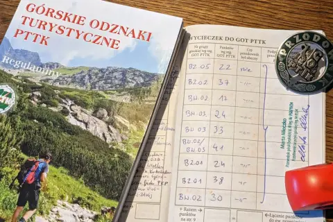 Książeczka GOT PTTK z wpisami wycieczek i odznaką przodownika.