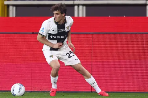 Piłkarz Parma Calcio 1913 z numerem 25 na koszulce w białym stroju z czarnymi elementami, gotowy do akcji na boisku.