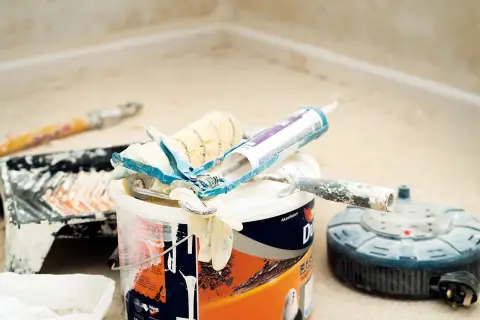 Narzędzia malarskie, puszka farby i pistolet do silikonu. Czy zapach farby jest szkodliwy? To pytanie zadaje sobie wielu majsterkowiczów.
