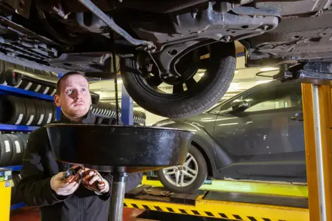 Mechanik wymienia olej w samochodzie. Zastanawiasz się, ile kosztuje serwis olejowo filtrowy?