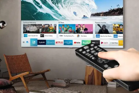 Smart TV z pilotem w dłoni, pokazujący aplikacje streamingowe. Czy smart TV potrzebuje anteny? Nie, jeśli korzystasz z internetu.