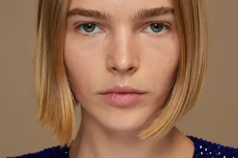 Primer plano de una mujer con un corte bob rubio y un vestido azul brillante.