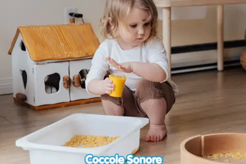 Bambina di 2 anni gioca con pasta in un vassoio, un'attività sensoriale divertente.