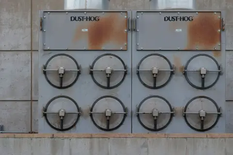 Dwa moduły przemysłowe DUST-HOG z ośmioma okrągłymi klapami, wykorzystujące zaawansowaną **technikę próżniową** do oczyszczania powietrza.