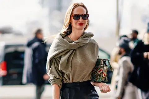 Mujer de unos 40 años con un look casual chic, gafas de sol, suéter gris y bolso estampado.