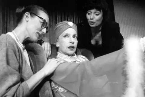 Marlena Milwiw młoda, w turbanie i perłach, z dwiema kobietami u boku, w teatralnej scenie.