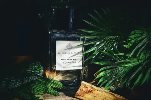Elegancka butelka perfum Bois Impérial otoczona bujną zielenią i kawałkiem drewna, przywołująca na myśl egzotyczny zapach akigalawood.