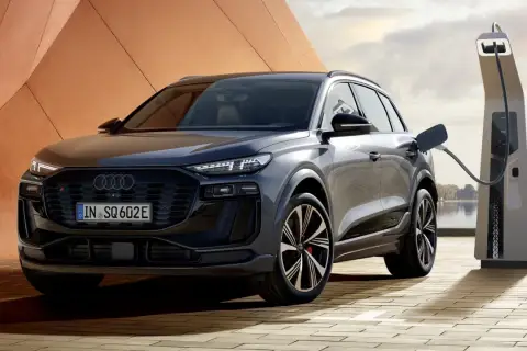 Elegancki Audi SQ6 z wtyczką ładowania podłączoną do stacji. Nowoczesny design i ekologiczna energia.