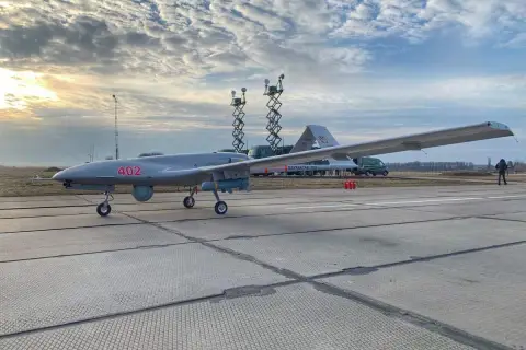 Szary dron Bayraktar TB-2 z numerem 402 na płycie lotniska, gotowy do akcji.