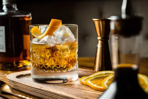 Cocktail con ghiaccio, scorza d'arancia e fette d'arancia. Ingredienti per un drink giapponese, con bottiglia di whisky e jigger in rame.