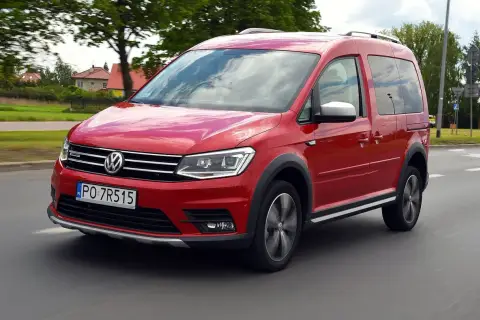 Czerwony Volkswagen Caddy 3 w ruchu, z widocznymi felgami i terenowym wyglądem.