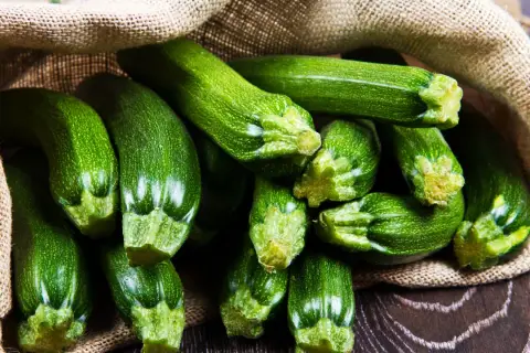 Frische, grüne Zucchini quellen aus einem Jutesack. Diese gesunde Gemüsesorte ist perfekt für leichte und nahrhafte Gerichte.