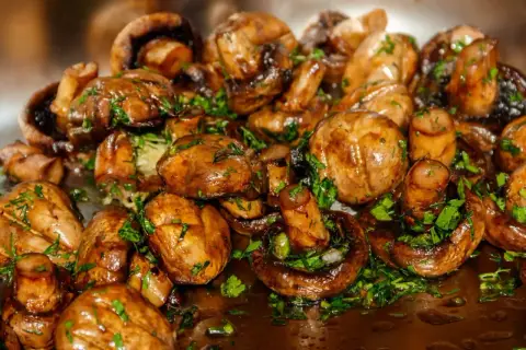 Champignons sautés, brillants et garnis de persil frais. Une recette simple et savoureuse pour sublimer ce légume.