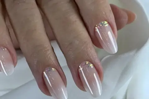 Elegancki manicure baby boomer z subtelnymi drobinkami brokatu na paznokciach.