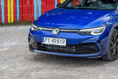 Niebieski Volkswagen z rejestracją PY 49819 stoi przed kolorowym płotem.