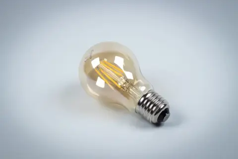 Szklana bańka żarówki LED z widocznymi drucikami, osadzona na metalowym gwincie.