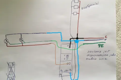 Schemat podłączenia przekaźnika bistabilnego do sterowania oświetleniem. Zasilanie 230V, przewody fazowy (brązowy), neutralny (niebieski) i ochronny (zielony).