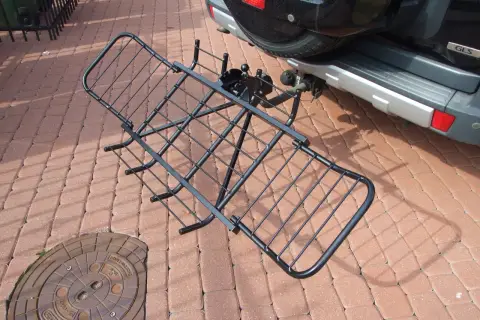 Czarny, metalowy uchwyt do przewozu motocykla na hak, gotowy do montażu przy samochodzie.