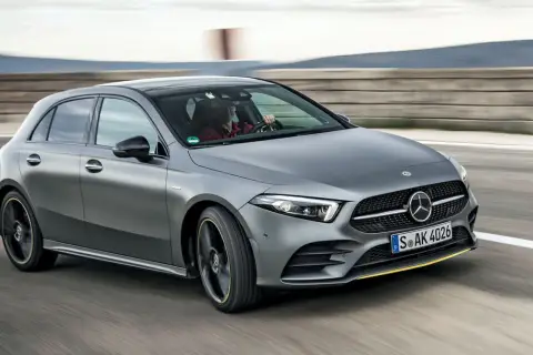Szary Mercedes W177 pędzi po torze, kierowca w czerwonej koszuli pewnie trzyma kierownicę.