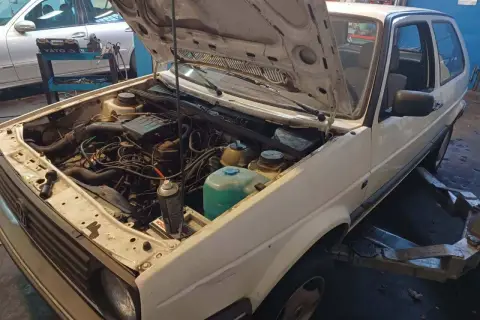 Biały Volkswagen Golf z otwartą maską, silnik gotowy do wyjęcia. Zastanawiasz się, ile kosztuje wyciągnięcie silnika?