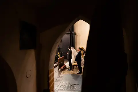 Para dowiedzieć się, jak zostać fotografem ślubnym, warto obserwować takie momenty. Para młoda w kościele, w otoczeniu gości.