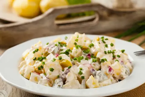 Pyszna, oryginalna kartoffelsalat z ziemniaków, ogórków kiszonych i cebuli, posypana szczypiorkiem.
