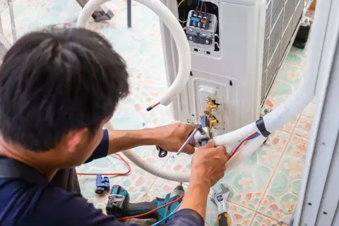 Technik montuje jednostkę klimatyzacyjną, dbając o prawidłowe odprowadzenie skroplin z klimatyzacji.