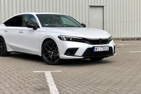 Biały Honda Civic 2025 z czarnymi felgami stoi na parkingu.