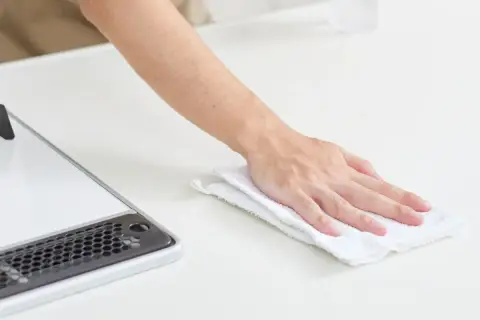 Mano limpiando una superficie blanca con un paño, como si fuera limpiar suelo de mármol.