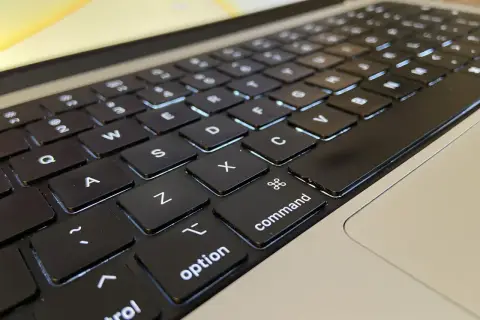 Klawiatura laptopa z podświetlanymi klawiszami. Widoczne litery Q, W, E, A, S, D, Z, X, C, a także klawisze "control", "option" i "command".